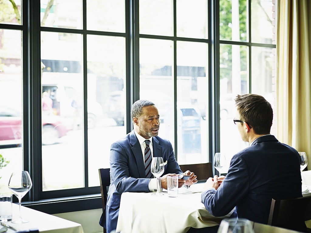 Two businessmen in discussion during business lunch at table in restaurant