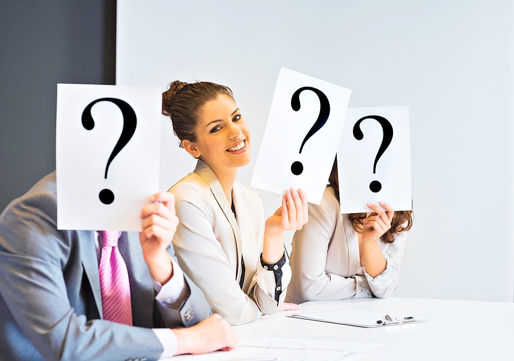 Three business people covering their faces with question mark